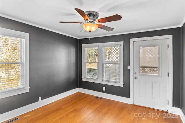 entrance foyer featuring ceiling fan, a wealth of natural light, ornamental molding, and hardwood / wood-style floors