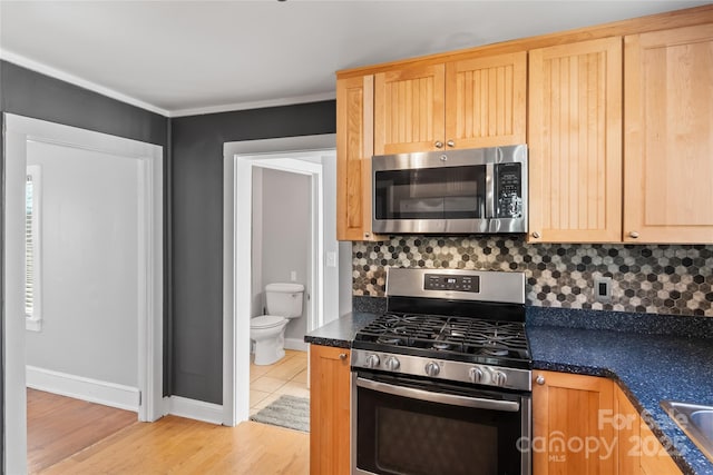 kitchen featuring decorative backsplash, light hardwood / wood-style floors, light brown cabinets, and stainless steel appliances