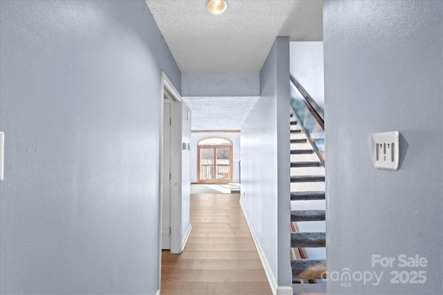 hall with hardwood / wood-style flooring and a textured ceiling