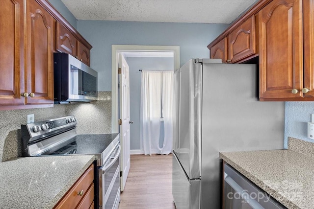 kitchen with light stone counters, stainless steel appliances, and a textured ceiling