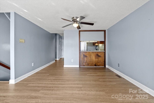 unfurnished living room featuring ceiling fan, light hardwood / wood-style floors, and a textured ceiling
