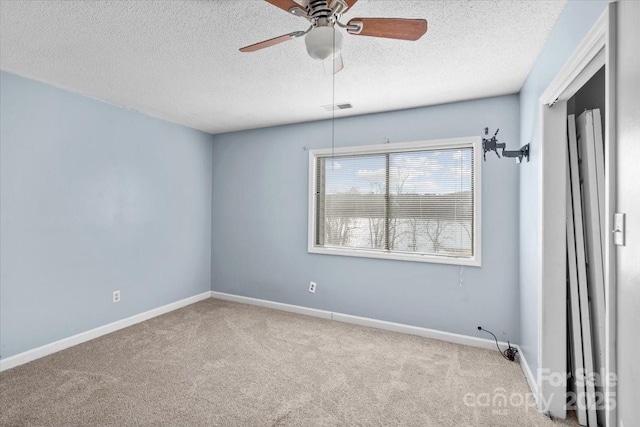 carpeted spare room featuring ceiling fan and a textured ceiling