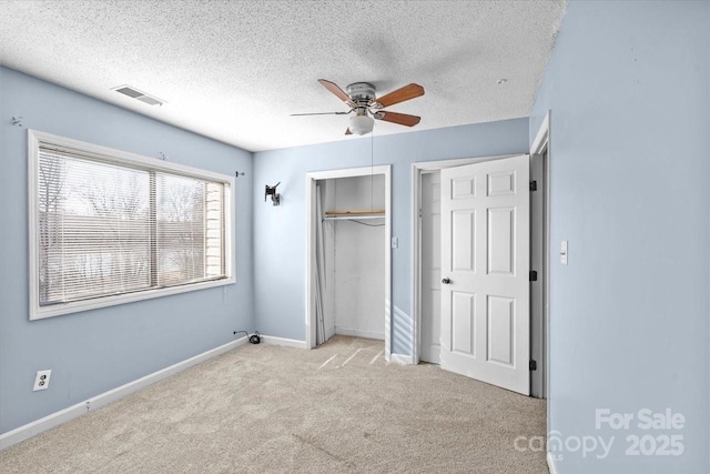 unfurnished bedroom with a textured ceiling, light colored carpet, a closet, and ceiling fan