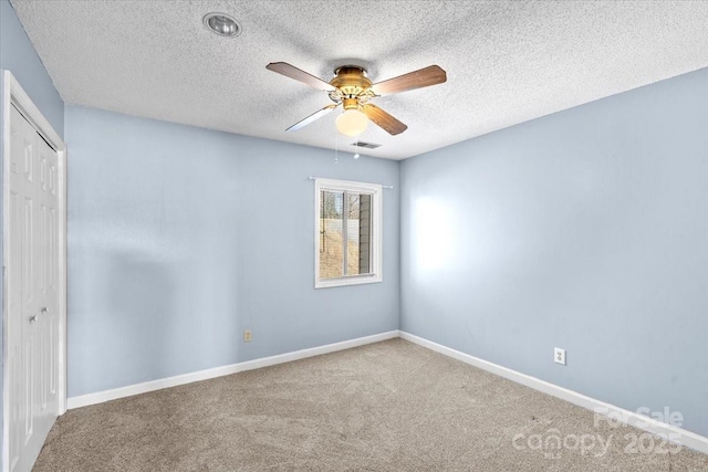 carpeted spare room featuring a textured ceiling and ceiling fan