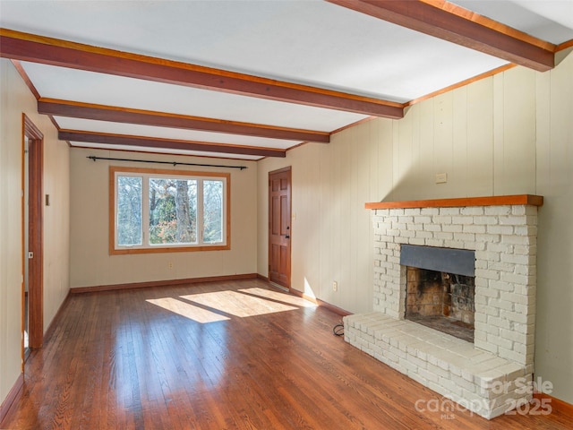 unfurnished living room with a brick fireplace, hardwood / wood-style flooring, and beamed ceiling