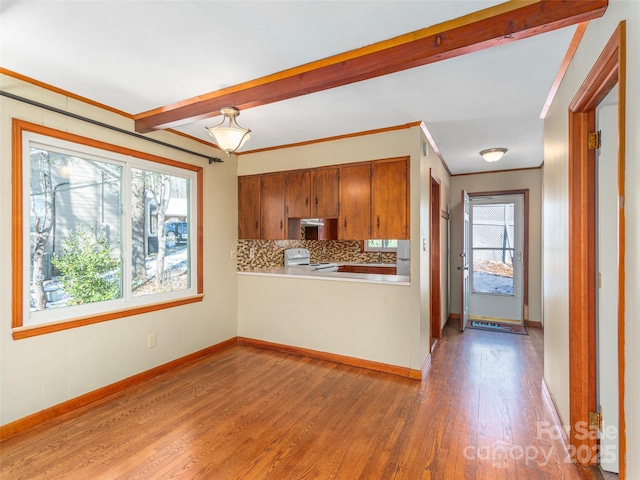 kitchen with white range with electric cooktop, tasteful backsplash, wood-type flooring, kitchen peninsula, and crown molding