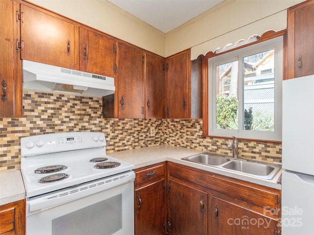 kitchen with tasteful backsplash, white appliances, and sink