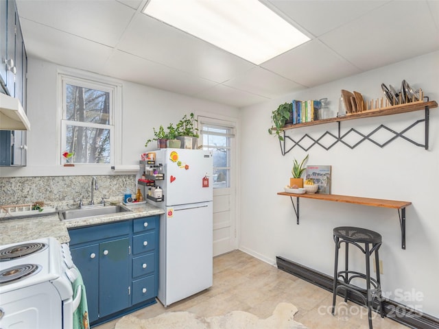 kitchen featuring white appliances, blue cabinets, sink, and a drop ceiling