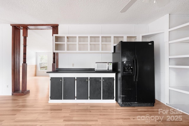 kitchen with ceiling fan, black fridge, hardwood / wood-style floors, and a textured ceiling