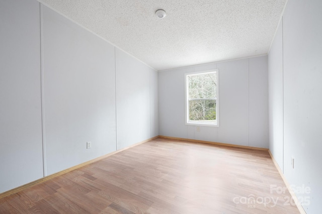 spare room with a textured ceiling and light hardwood / wood-style floors