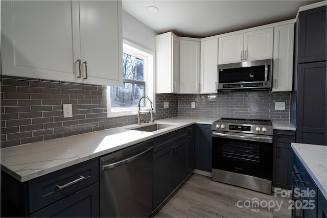 kitchen featuring decorative backsplash, sink, white cabinets, and appliances with stainless steel finishes