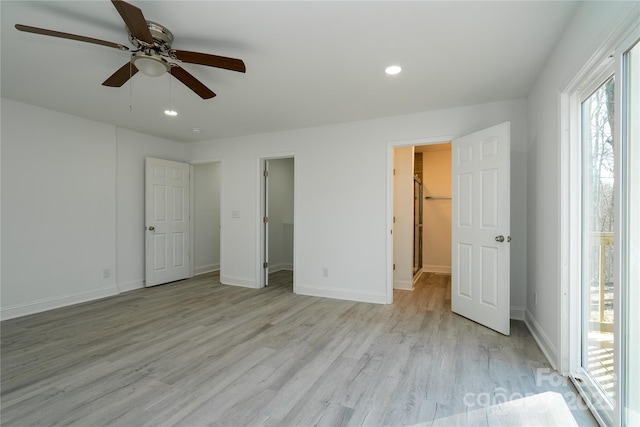 unfurnished bedroom with light hardwood / wood-style flooring, ceiling fan, and a walk in closet