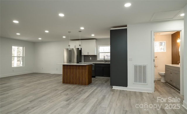 kitchen with high quality fridge, a center island, white cabinetry, decorative light fixtures, and backsplash