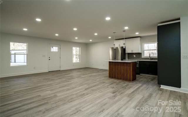 kitchen featuring a center island, light hardwood / wood-style floors, high end fridge, hanging light fixtures, and sink