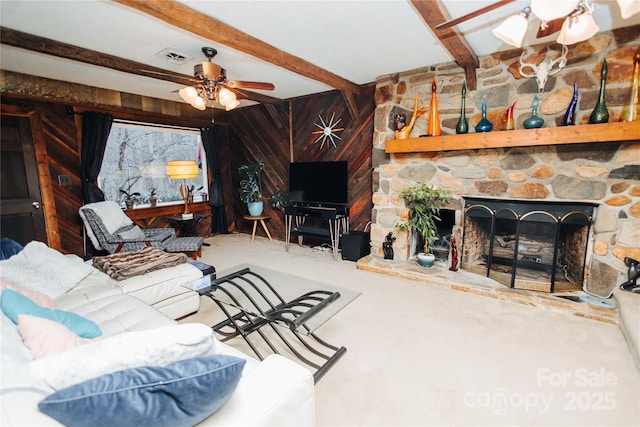 living area with carpet floors, beam ceiling, a fireplace, and a ceiling fan