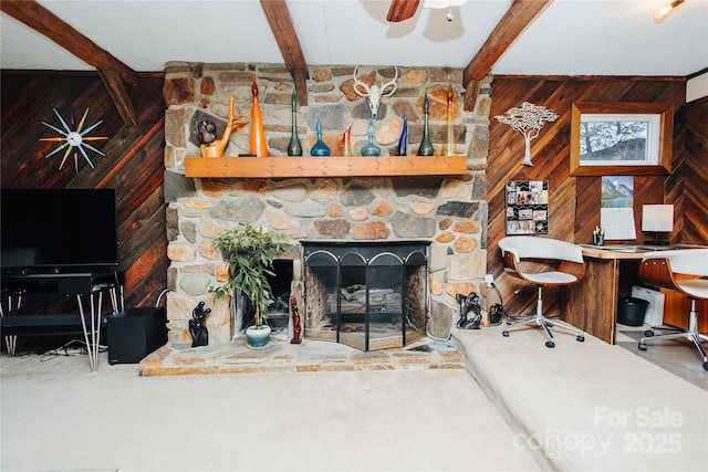 carpeted living room featuring ceiling fan, a fireplace, beam ceiling, and wooden walls