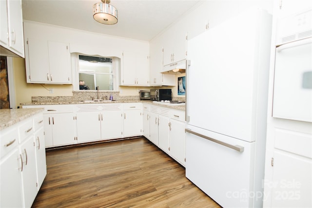 kitchen featuring a sink, white cabinetry, freestanding refrigerator, dark wood-style floors, and crown molding