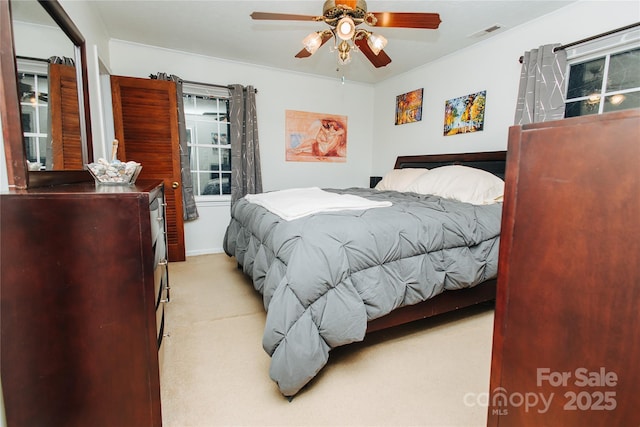 bedroom featuring ceiling fan, visible vents, and light colored carpet