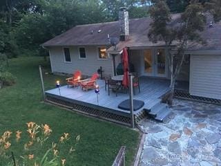 rear view of house with a fire pit, a yard, a chimney, and a wooden deck