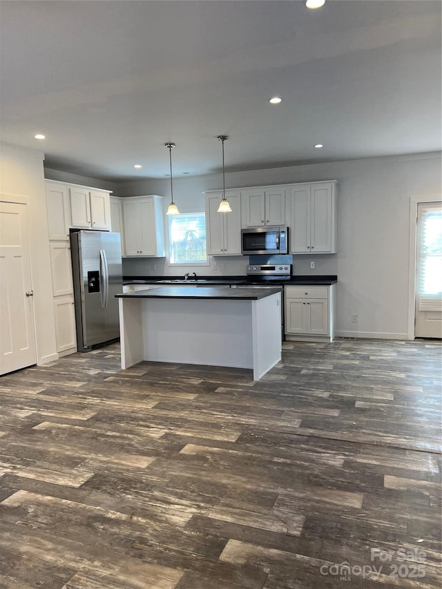 kitchen featuring dark countertops, dark wood-style floors, appliances with stainless steel finishes, and a wealth of natural light