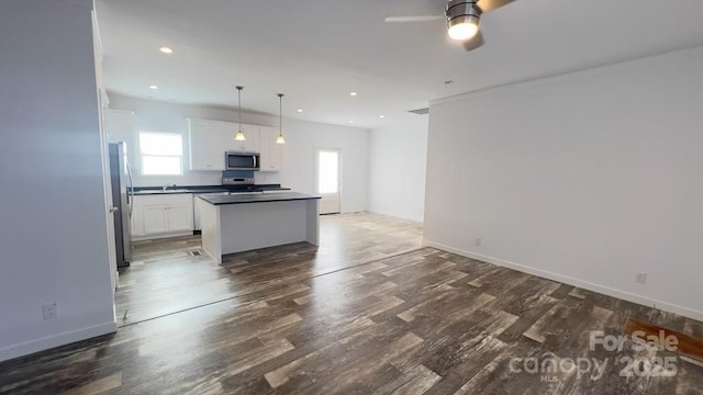 kitchen with a kitchen island, appliances with stainless steel finishes, open floor plan, dark wood-style flooring, and white cabinetry