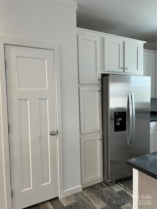 kitchen with dark countertops, dark wood-style flooring, white cabinetry, and stainless steel refrigerator with ice dispenser