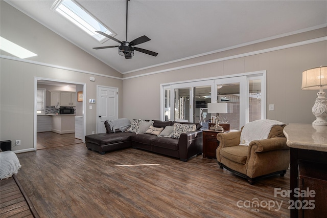 living room featuring a wealth of natural light, a skylight, dark hardwood / wood-style floors, ceiling fan, and crown molding