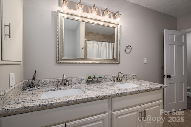 bathroom with a textured ceiling, walk in shower, and vanity