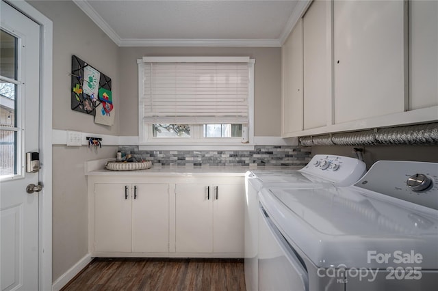 laundry area featuring washing machine and clothes dryer, dark hardwood / wood-style flooring, ornamental molding, and cabinets