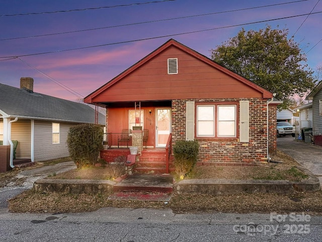 bungalow-style home with a porch and brick siding