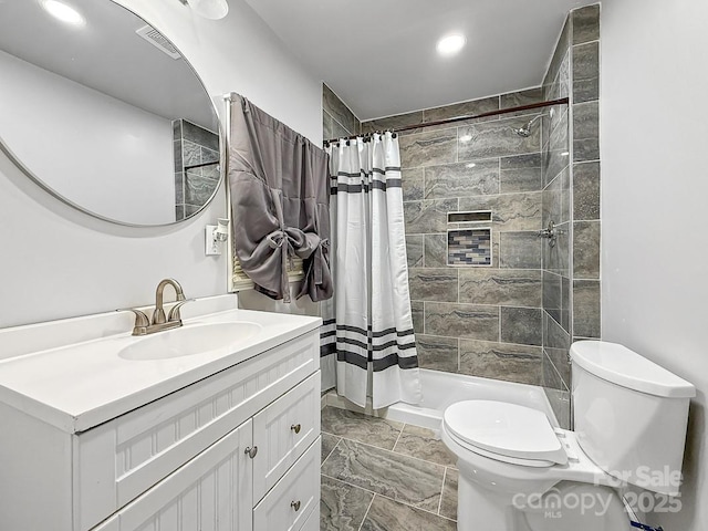 full bath featuring toilet, visible vents, tiled shower, and vanity