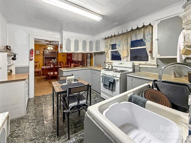 kitchen featuring white cabinets, light countertops, ceiling fan, and white gas range oven