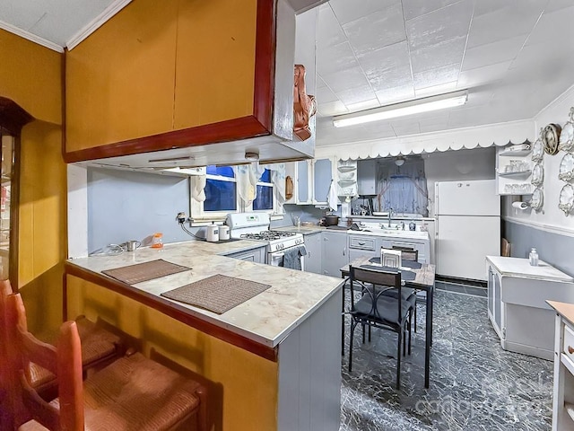 kitchen with white appliances, ornamental molding, a peninsula, light countertops, and a sink