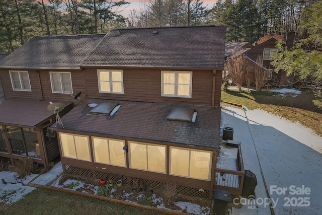 back house at dusk with cooling unit and a sunroom