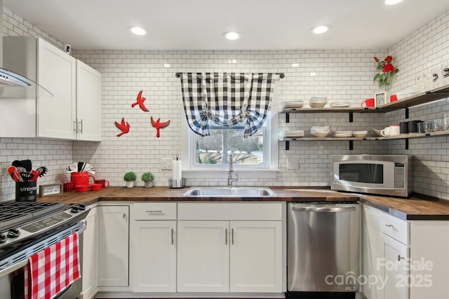 kitchen featuring sink, white cabinetry, backsplash, stainless steel appliances, and wood counters