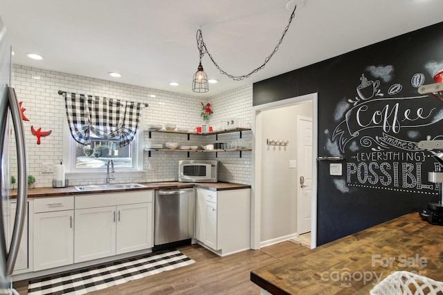 kitchen with sink, wooden counters, stainless steel appliances, light hardwood / wood-style floors, and white cabinets