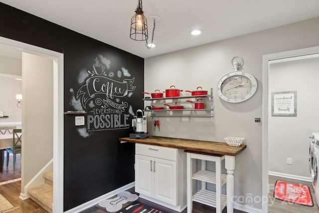 bar with dark wood-type flooring, washing machine and clothes dryer, butcher block countertops, white cabinetry, and decorative light fixtures