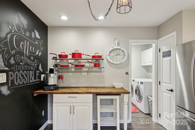 kitchen with independent washer and dryer, white cabinets, wooden counters, and stainless steel refrigerator