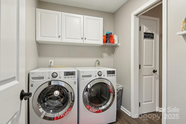 clothes washing area featuring dark wood-type flooring, cabinets, and washer and clothes dryer