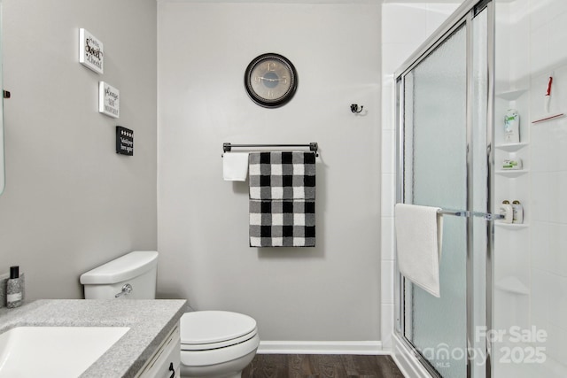 bathroom featuring vanity, hardwood / wood-style flooring, a shower with door, and toilet