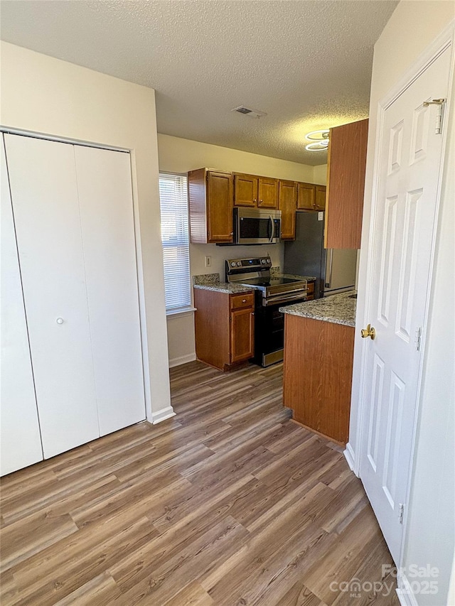 kitchen with light hardwood / wood-style flooring, stainless steel appliances, and a textured ceiling