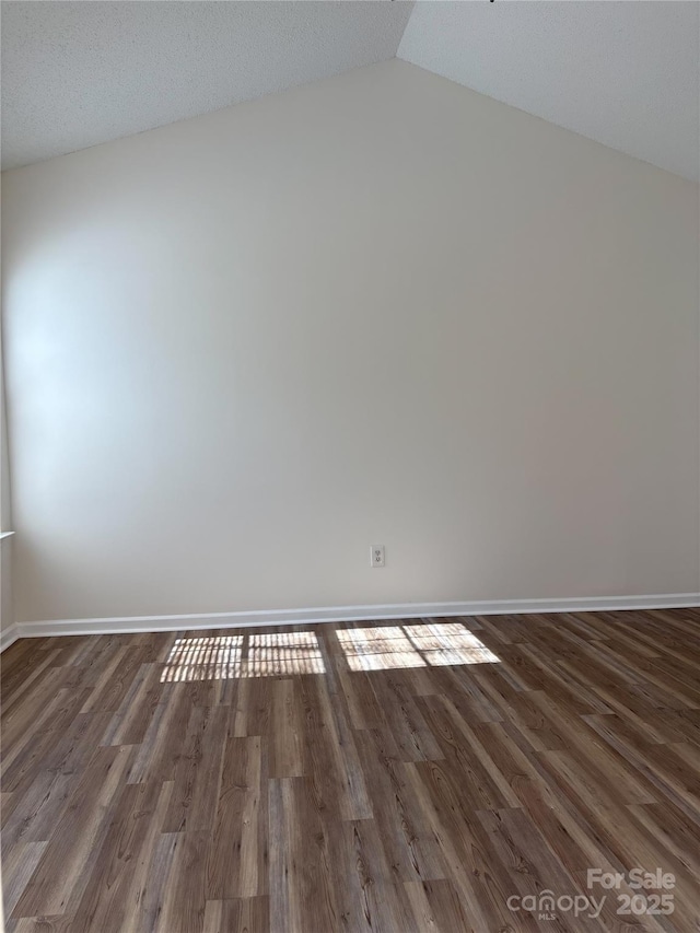 empty room featuring dark hardwood / wood-style flooring, vaulted ceiling, and a textured ceiling