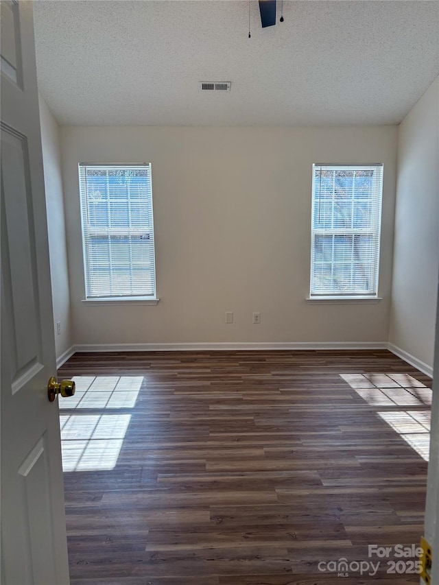 spare room with ceiling fan, dark wood-type flooring, and a textured ceiling