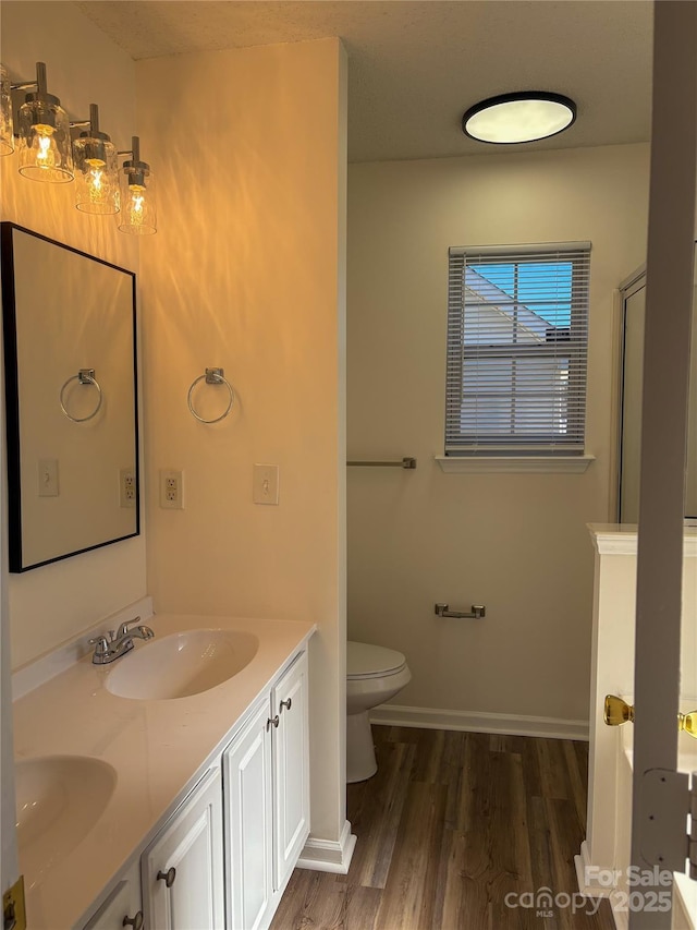 bathroom featuring vanity, hardwood / wood-style floors, walk in shower, and toilet