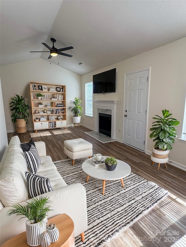 living room featuring hardwood / wood-style flooring, a premium fireplace, lofted ceiling, and ceiling fan