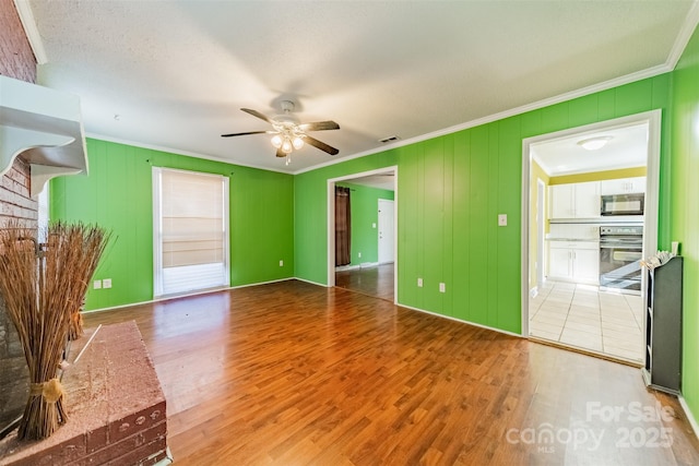 unfurnished living room featuring hardwood / wood-style flooring, ornamental molding, and ceiling fan