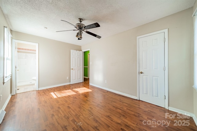 unfurnished bedroom featuring connected bathroom, a textured ceiling, wood-type flooring, and ceiling fan