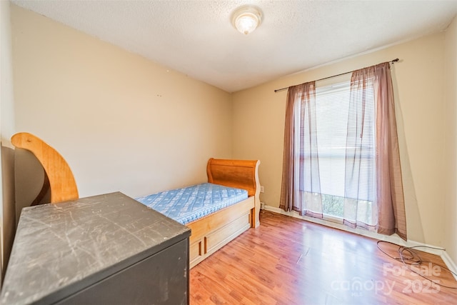 bedroom featuring a textured ceiling, multiple windows, and light wood-type flooring