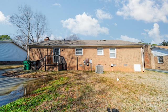 back of house with central AC unit and a lawn