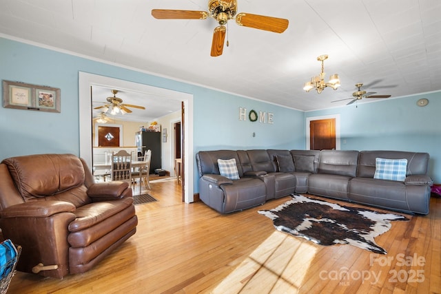 living room featuring ceiling fan with notable chandelier, ornamental molding, and wood-type flooring